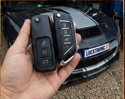Coded flip keys held in front of a customer's sports car